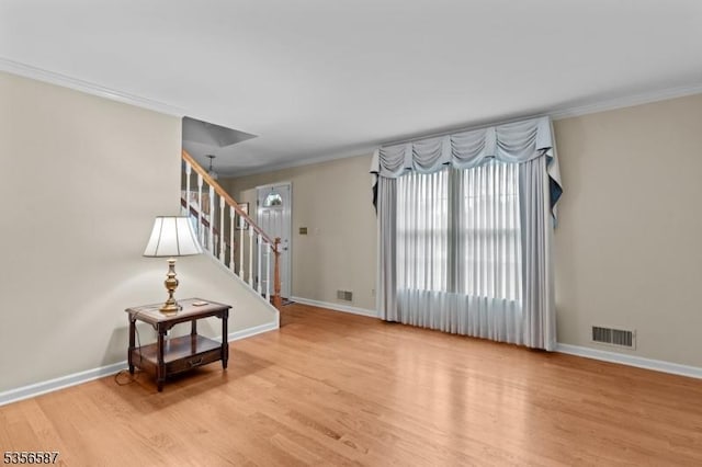 foyer with stairs, wood finished floors, plenty of natural light, baseboards, and ornamental molding