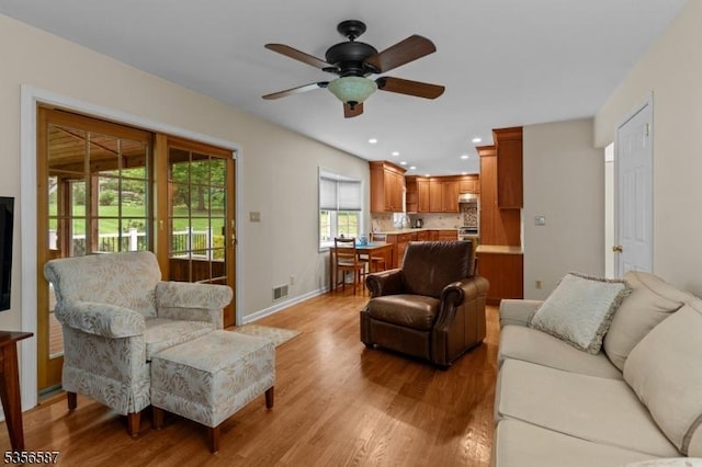 living area featuring ceiling fan, light wood-style flooring, recessed lighting, and baseboards