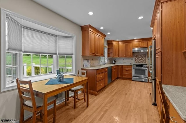 kitchen featuring stainless steel appliances, under cabinet range hood, brown cabinets, open shelves, and light wood finished floors