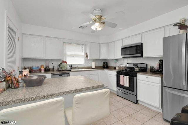 127 Brill St, Newark City, NJ 07105 - kitchen featuring stainless steel appliances, white cabinetry, decorative backsplash, and light tile patterned floors