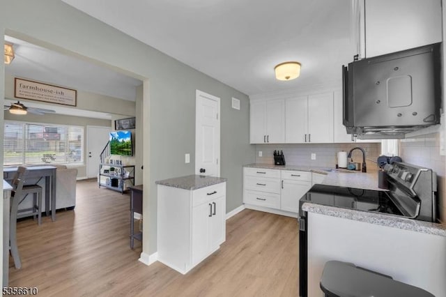 kitchen with a sink, stainless steel electric range, light wood-style flooring, and tasteful backsplash