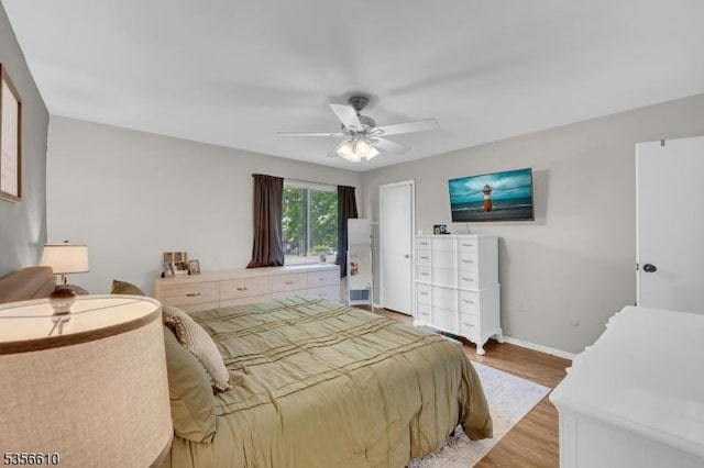 bedroom featuring light wood-style flooring, baseboards, and a ceiling fan