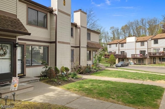 view of side of property featuring a chimney, a yard, and a residential view
