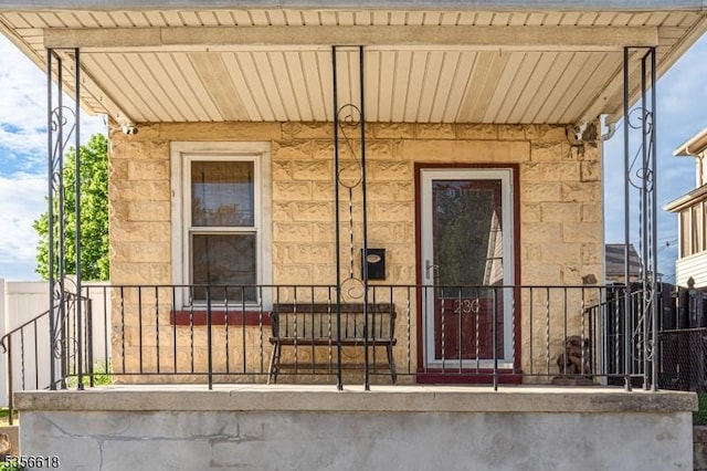 doorway to property with stone siding and fence