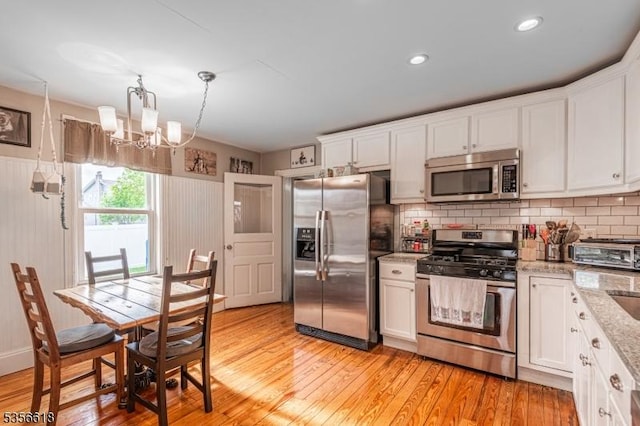 kitchen featuring appliances with stainless steel finishes, a chandelier, light wood-style flooring, white cabinets, and recessed lighting