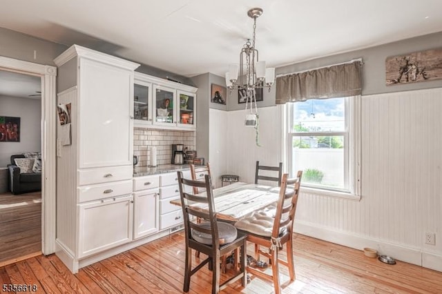dining room with a chandelier, light wood-style floors, and baseboards