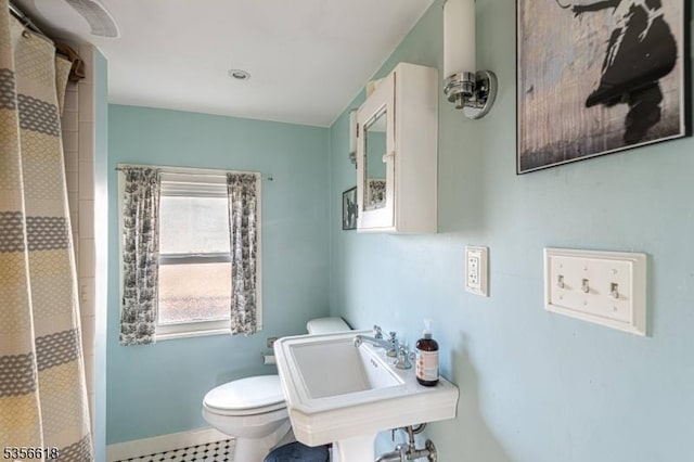 bathroom with toilet, curtained shower, and a sink