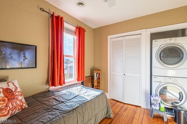 bedroom with estacked washer and dryer, a closet, and wood finished floors