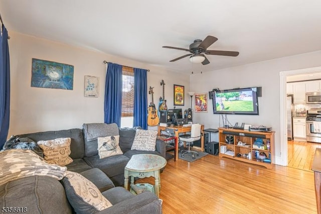 living area featuring light wood finished floors, a ceiling fan, and a desk