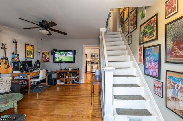 stairway featuring wood finished floors and ceiling fan