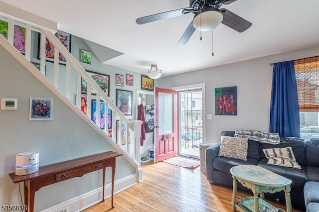 living area with wood finished floors, stairs, and a ceiling fan