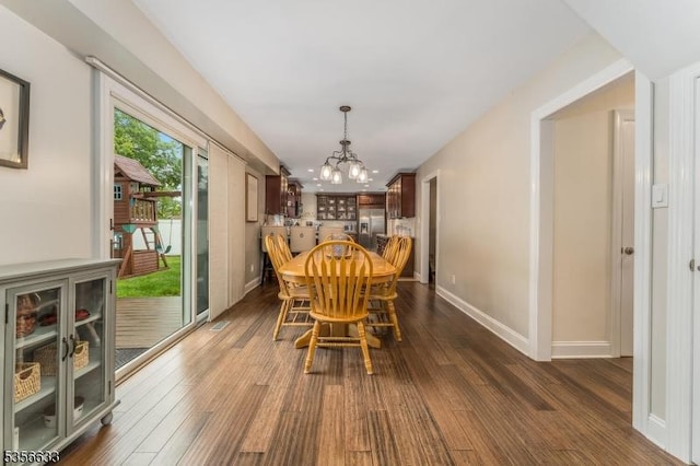 dining room featuring a chandelier, dark wood-style floors, and baseboards