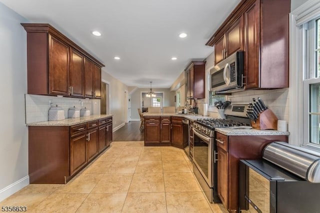 kitchen featuring stainless steel appliances, a peninsula, baseboards, backsplash, and recessed lighting