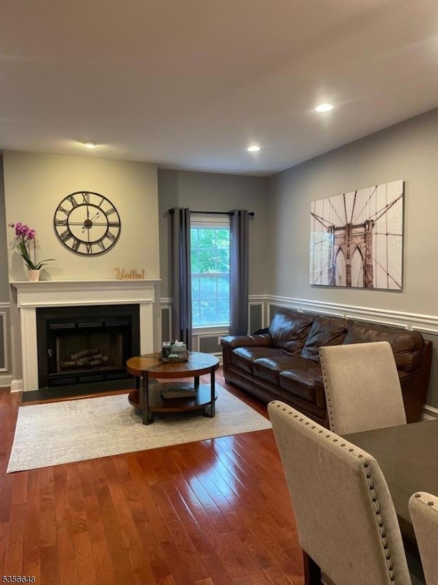 living area with a fireplace, hardwood / wood-style floors, recessed lighting, and a wainscoted wall