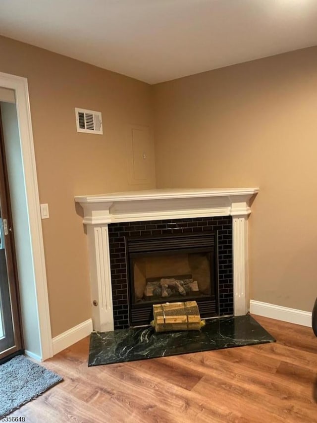 detailed view of a tile fireplace, wood finished floors, and baseboards