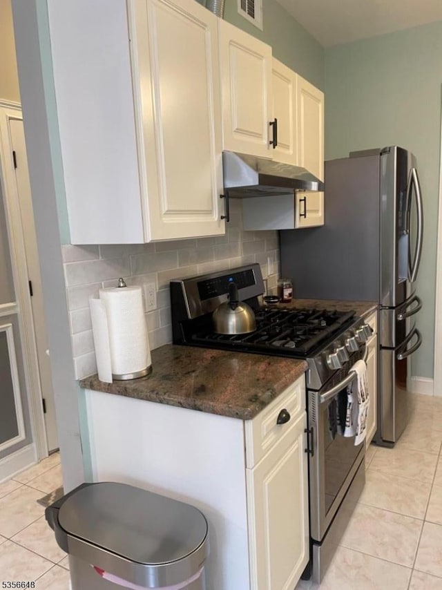 kitchen featuring stainless steel range with gas stovetop, under cabinet range hood, tasteful backsplash, and light tile patterned floors