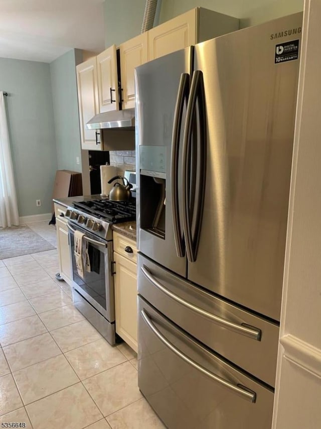 kitchen featuring appliances with stainless steel finishes, under cabinet range hood, light tile patterned floors, baseboards, and tasteful backsplash