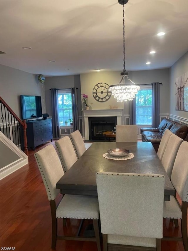 dining space featuring a fireplace, healthy amount of natural light, wood finished floors, recessed lighting, and stairway