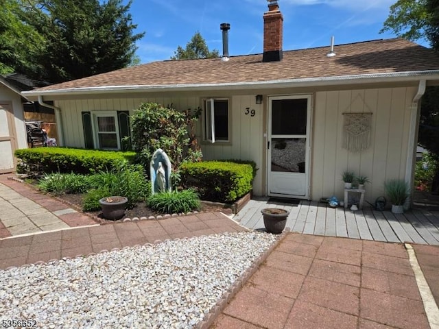 view of front of home featuring a chimney, a shingled roof, and board and batten siding