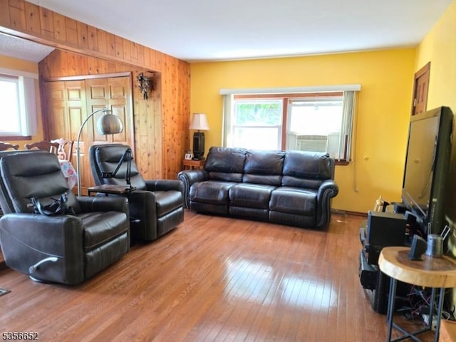 living area with healthy amount of natural light, hardwood / wood-style floors, and wooden walls