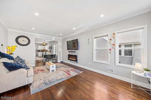 living area featuring wood finished floors, ornamental molding, baseboards, and recessed lighting