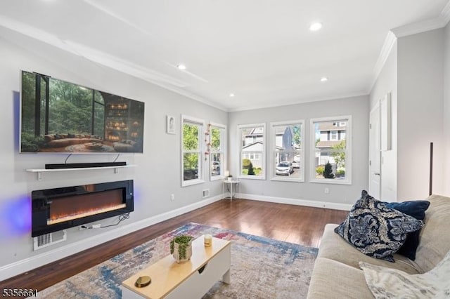 living room with ornamental molding, a glass covered fireplace, wood finished floors, baseboards, and recessed lighting