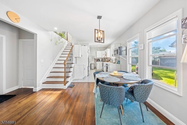 dining space featuring stairs, dark wood-type flooring, baseboards, and a chandelier