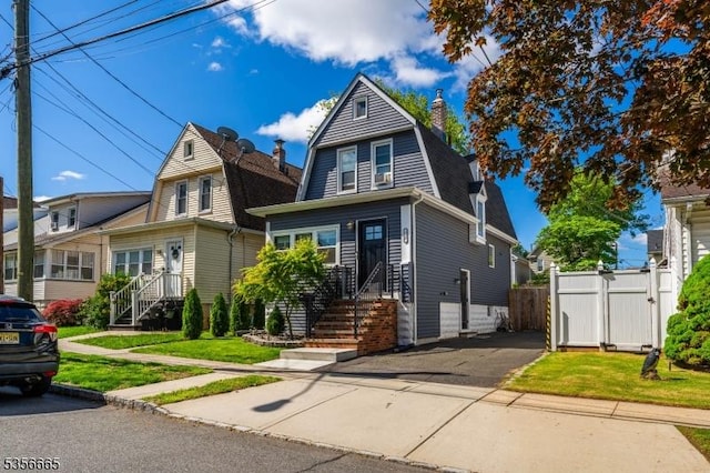 view of front of home featuring a gambrel roof, a chimney, entry steps, and driveway
