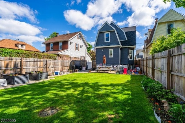 rear view of house featuring a vegetable garden, a patio area, a gambrel roof, and roof with shingles