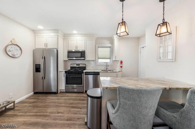 kitchen featuring appliances with stainless steel finishes, dark wood-type flooring, a sink, white cabinetry, and backsplash