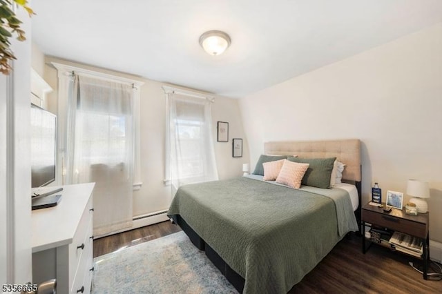 bedroom featuring multiple windows, dark wood-style floors, and a baseboard heating unit