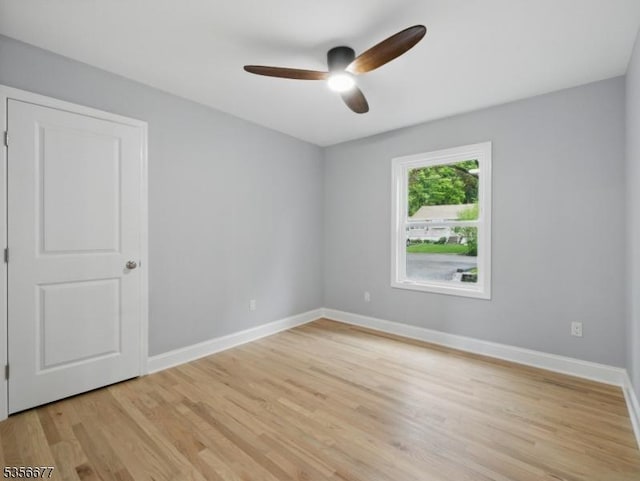 unfurnished room with ceiling fan, light wood-type flooring, and baseboards