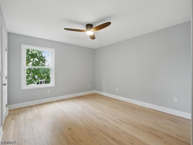 spare room featuring a ceiling fan, baseboards, and light wood-type flooring