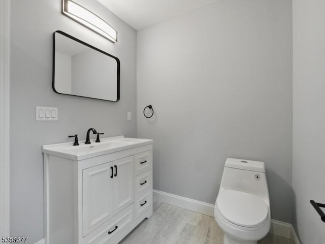 bathroom featuring baseboards, toilet, and vanity