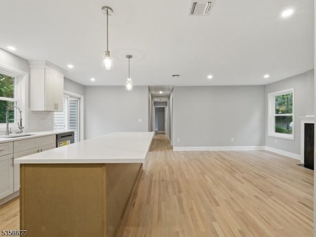 kitchen with a sink, a center island, light countertops, light wood-type flooring, and recessed lighting