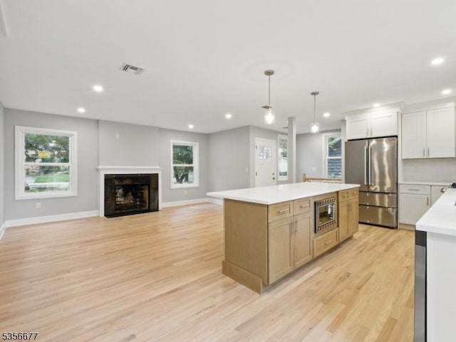 kitchen with stainless steel appliances, light wood-type flooring, recessed lighting, light countertops, and a center island