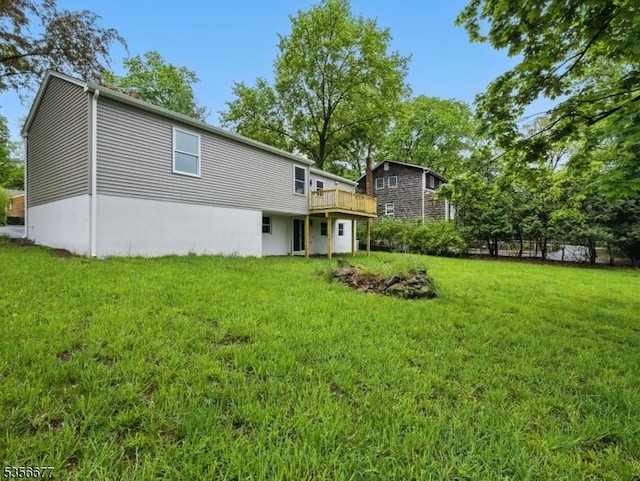 rear view of property featuring a lawn and a wooden deck