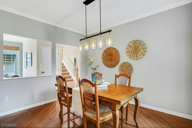 dining space with wood finished floors, baseboards, ornamental molding, and stairway