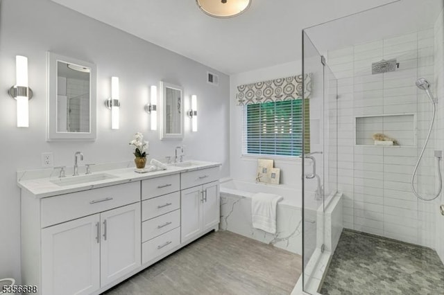 bathroom featuring a stall shower, double vanity, and a garden tub