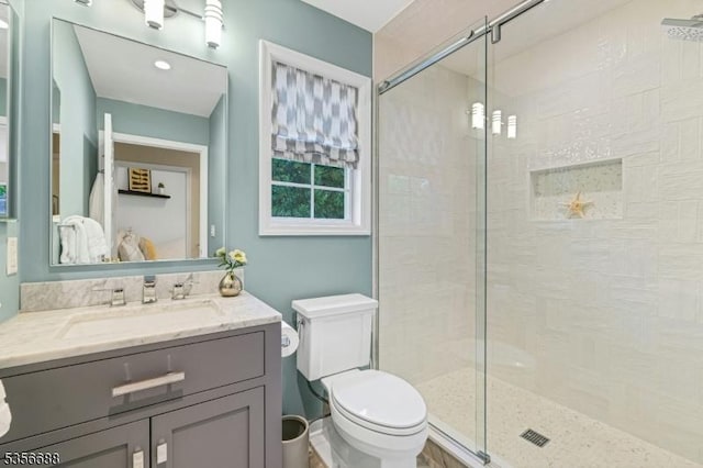 bathroom with a stall shower, toilet, and vanity