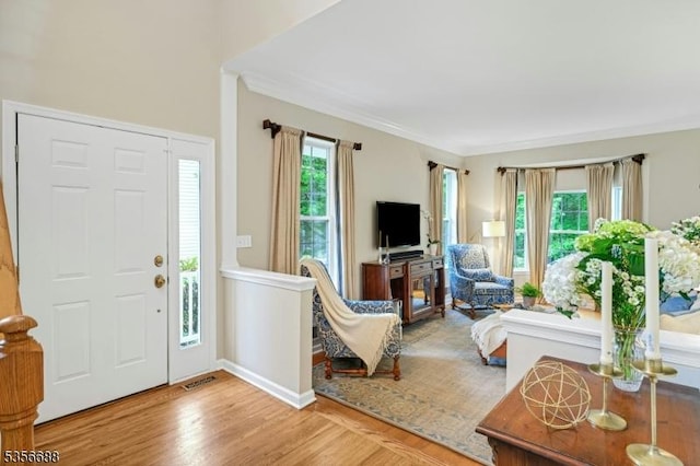 foyer with wood finished floors and crown molding