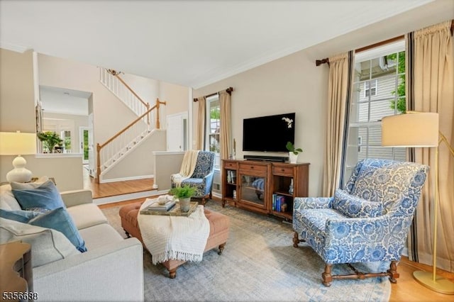 living area with stairs, wood finished floors, and crown molding