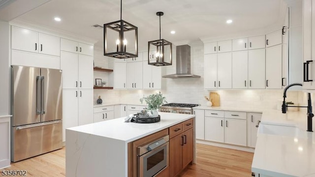 kitchen featuring stainless steel appliances, wall chimney range hood, open shelves, a center island, and light wood-style flooring