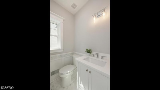 bathroom with toilet, a wainscoted wall, and vanity