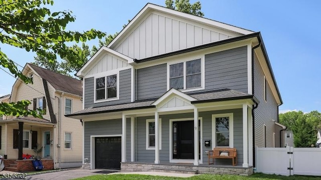 craftsman inspired home featuring board and batten siding, covered porch, a garage, fence, and driveway