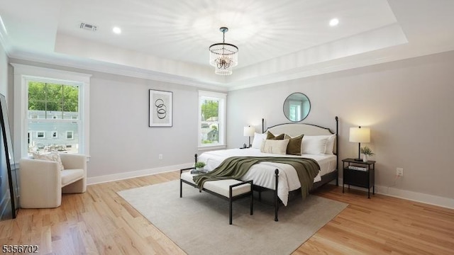 bedroom with a tray ceiling, multiple windows, and a chandelier