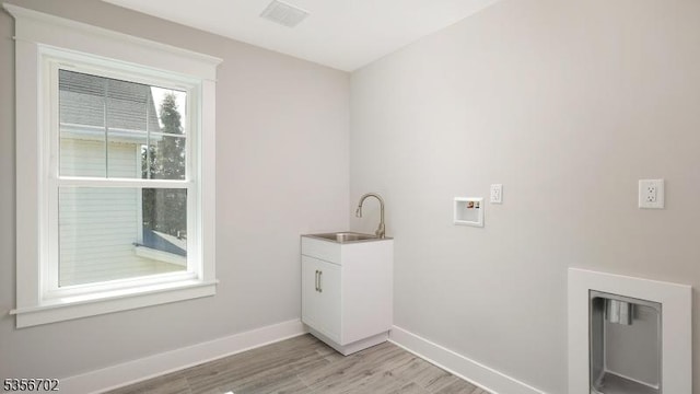 laundry area with light wood-style floors, baseboards, cabinet space, and hookup for a washing machine