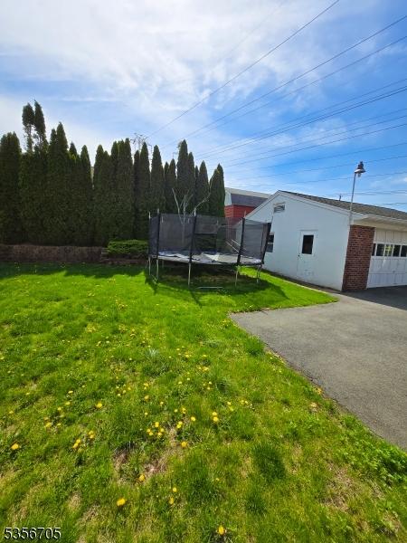 50 Newark Pl, Belleville Twp, NJ 07109 - view of green lawn featuring a trampoline and asphalt driveway