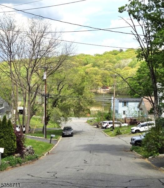 view of asphalt street with curbs, street lights, and a wooded view