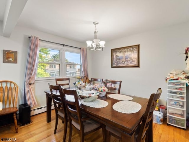 dining room featuring a chandelier, light wood finished floors, and baseboard heating